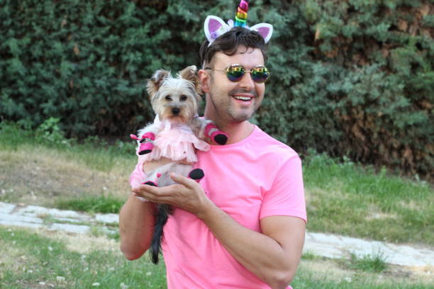 Playful man in pink with unicorn ears and dog in tutu outdoors.