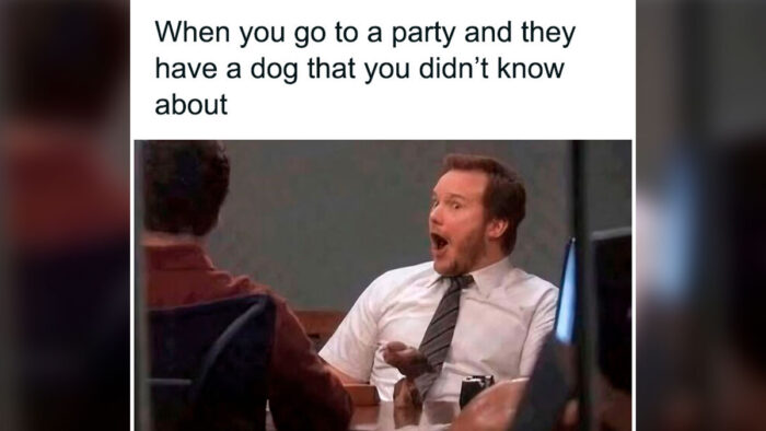 Man excitedly surprised by unexpected dog at lively party gathering.