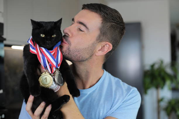 Happy man kisses proud black cat with medals in modern home.