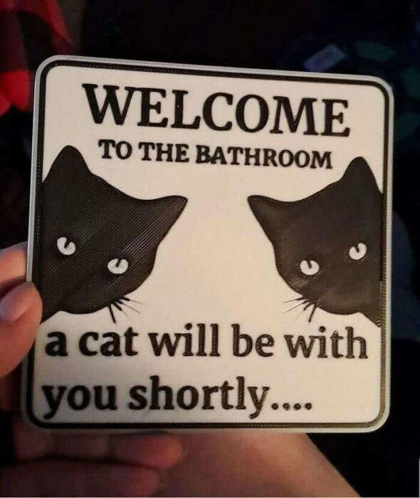 Welcome bathroom cat sign with black cat silhouettes and humorous pet decor message.